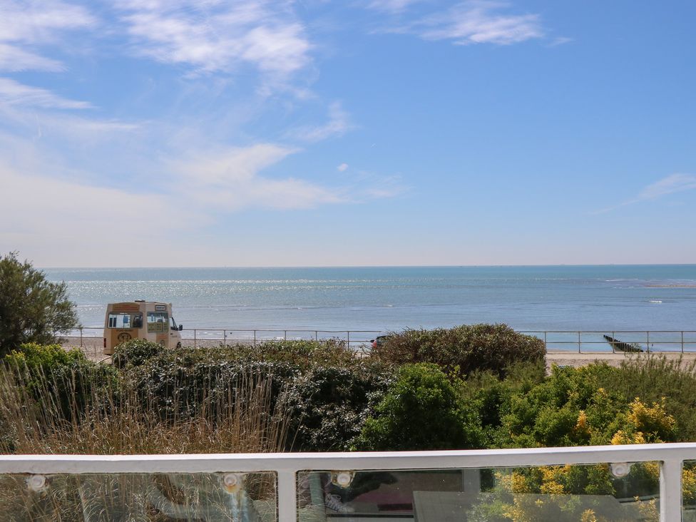 A view of the sea and beach with vegetation and a food truck at Bella vista in Selsey, West Sussex