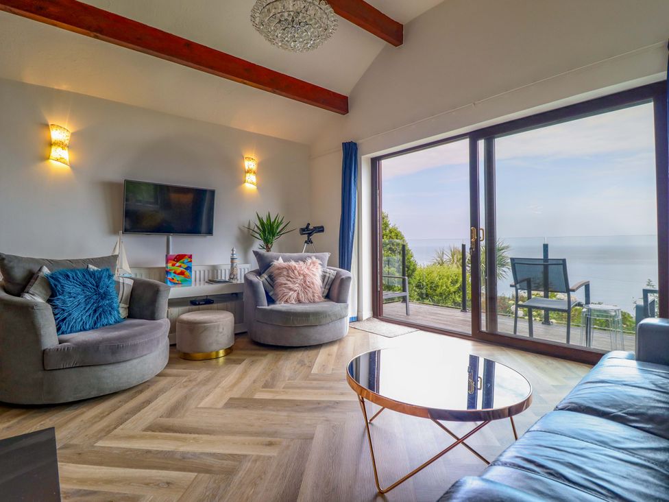 A living room with a television, armchairs, and a coffee table at Ser a Mor (Stars and Sea) Bull Bay near Amlwch