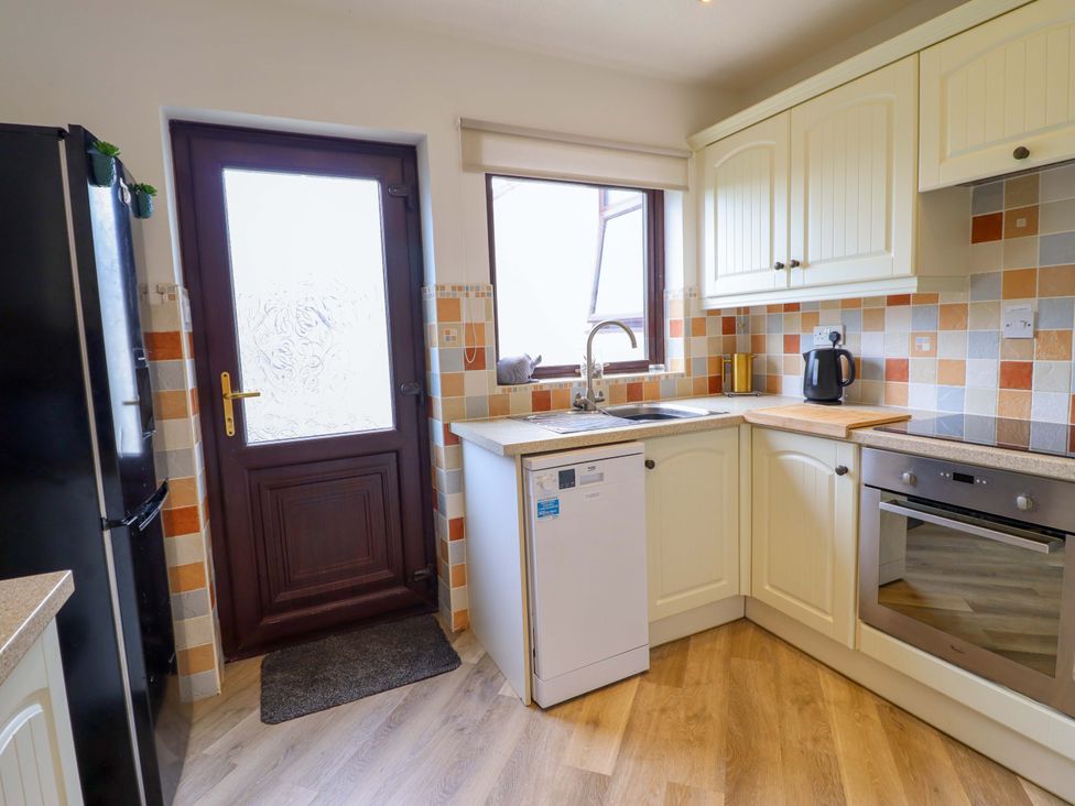 A kitchen with a sink, oven, and fridge at Ser a Mor (Stars and Sea) Bull Bay near Amlwch