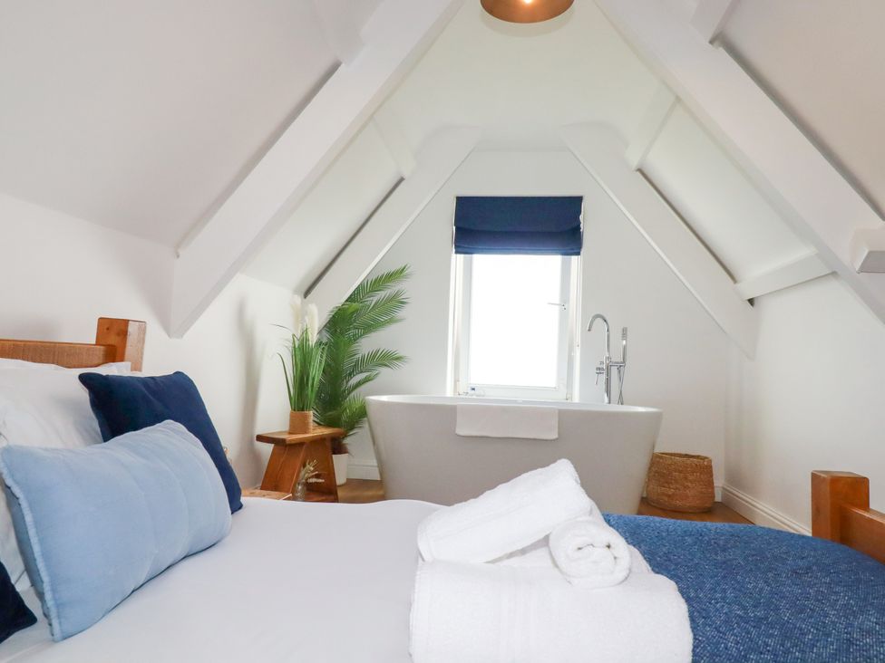 A bedroom with a bathtub and plant at 5 St Gwithian Apartments