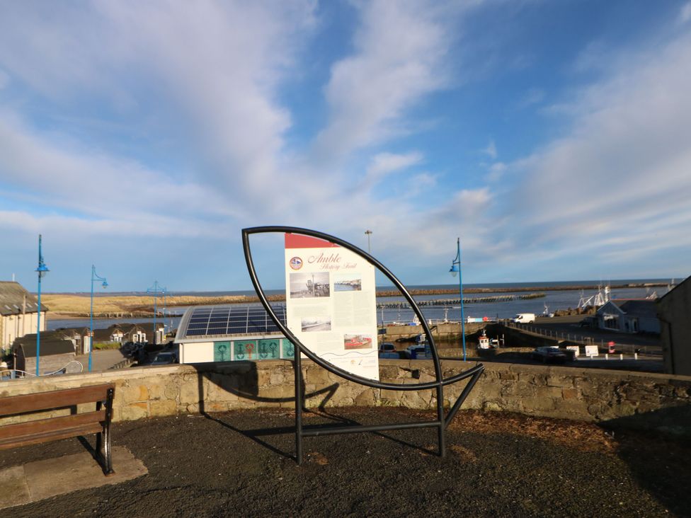 An information board and a bench overlooking water at Mulberry House Amble