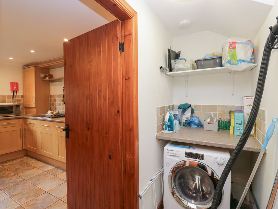 A laundry room with a washing machine and shelf at Low Dow Crag in Coniston
