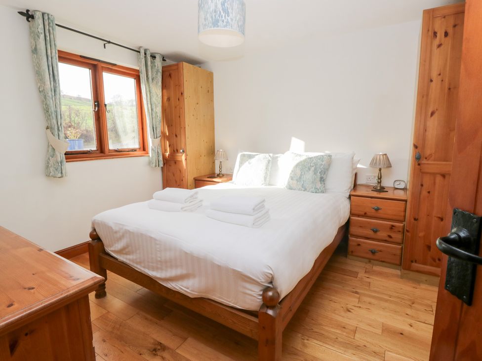 A bedroom with a bed and wooden furniture at Low Dow Crag in Coniston