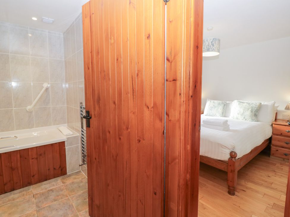 A bathroom with a bathtub and a bedroom visible at Low Dow Crag in Coniston