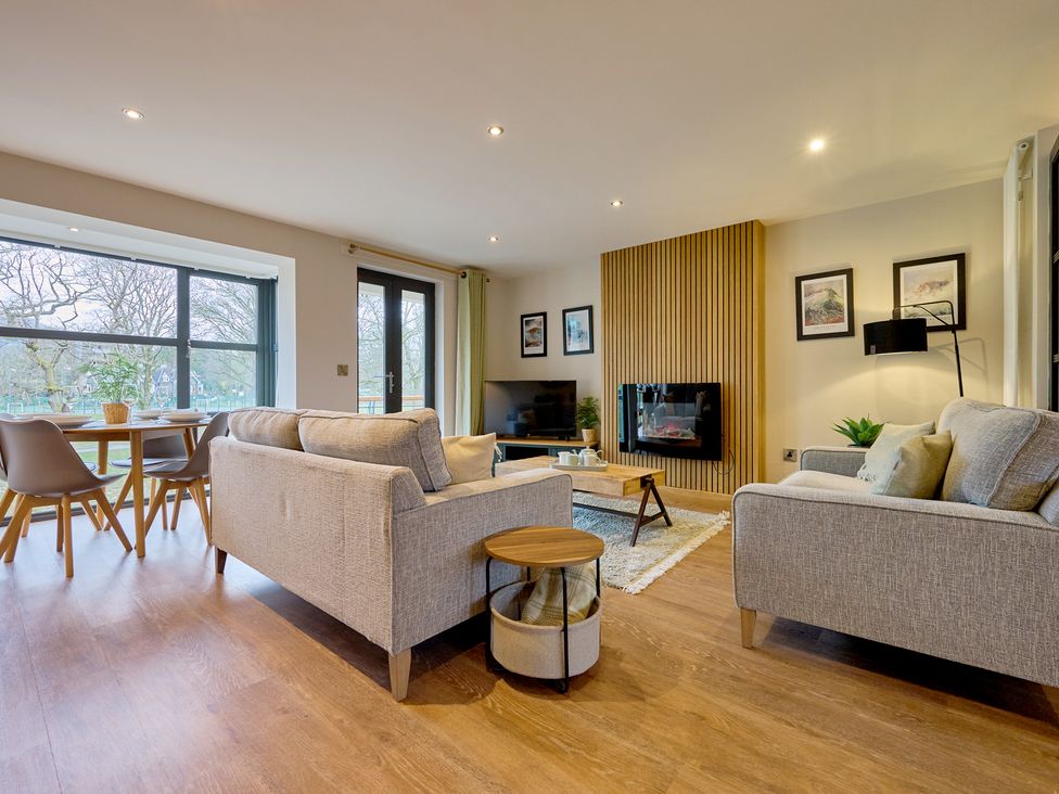 A living room with a sofa, chairs, coffee table and television at Riverside Park 3 in Keswick