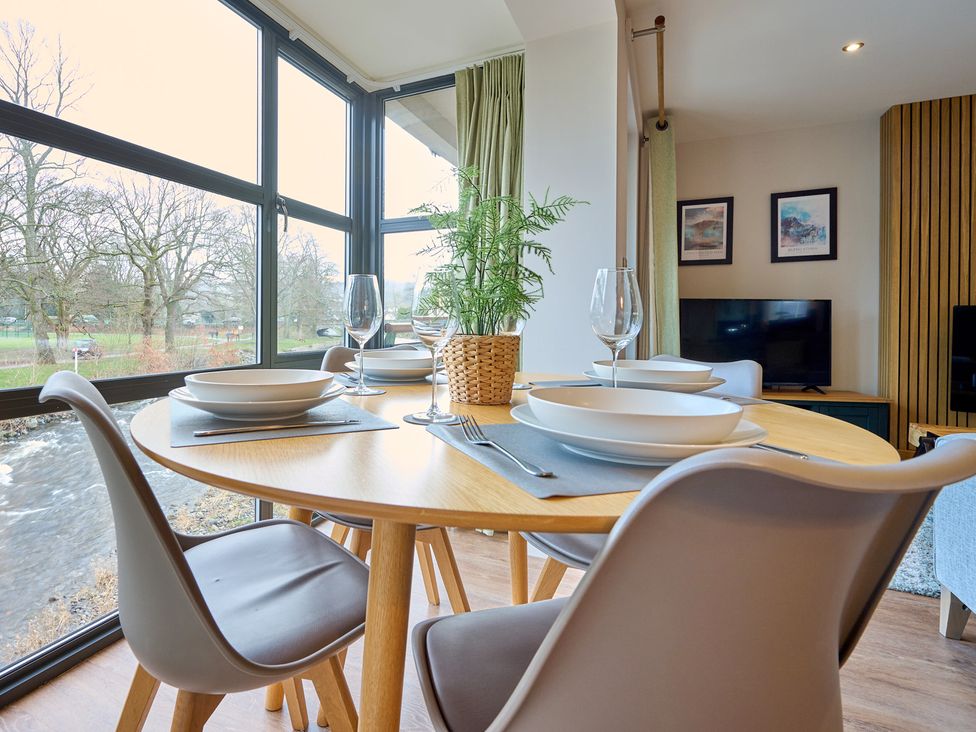 A dining room with a round table set for meals at Riverside Park 3 in Keswick