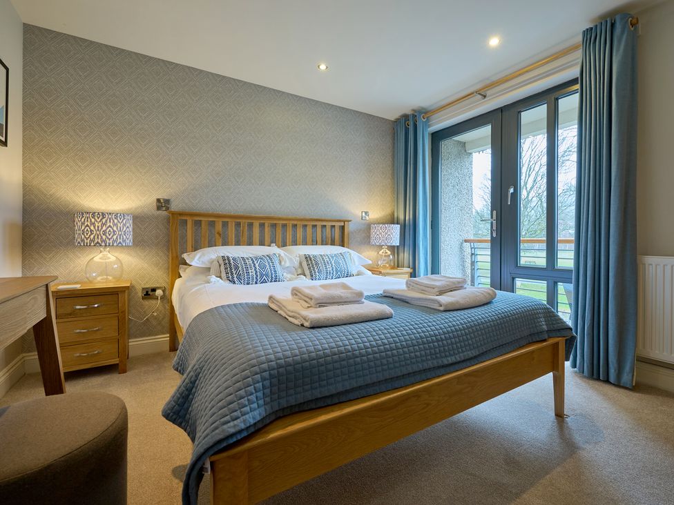 A bedroom with a bed, bedside table, and dresser at Riverside Park 3 in Keswick