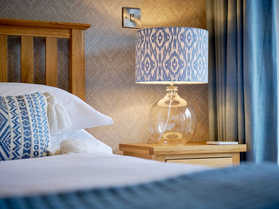A bedroom with a lamp on a bedside table at Riverside Park 3 in Keswick