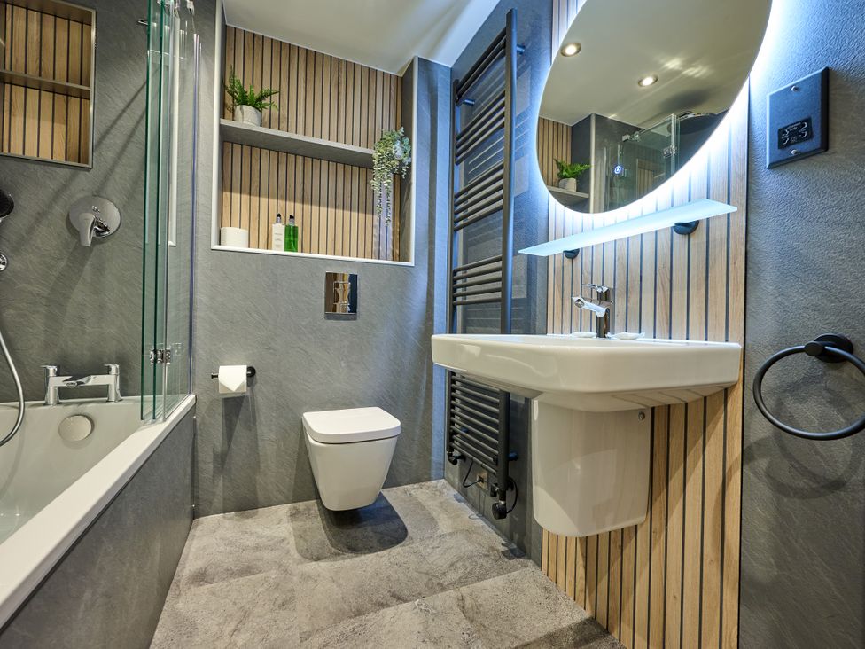 A bathroom with a bathtub, toilet, and sink at Riverside Park 5 in Keswick