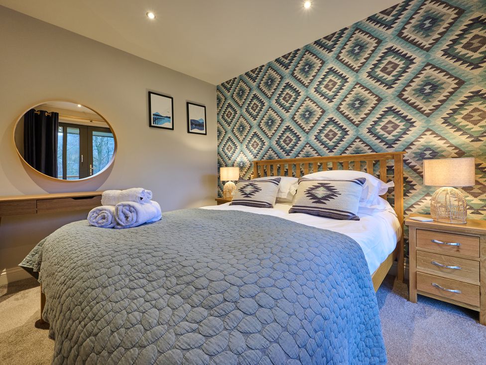 A bedroom with a bed and bedside table at Riverside Park 5 Keswick