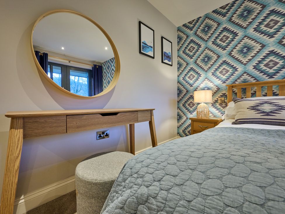 A bedroom with a bed and a dressing table at Riverside Park 5 in Keswick