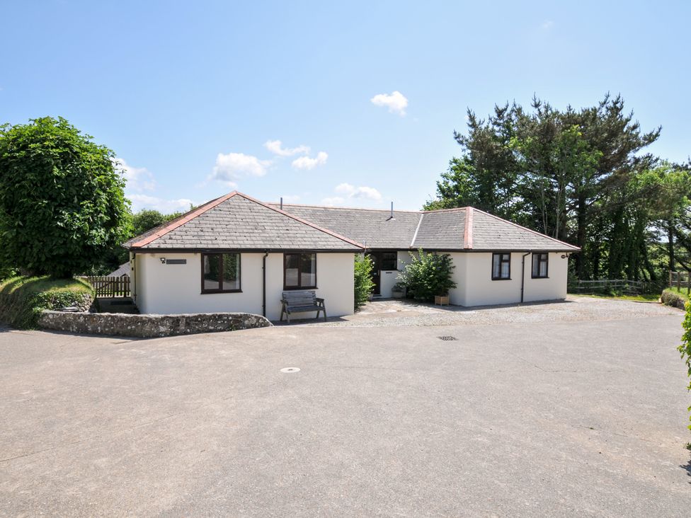 A house with a bench and trees in front at Columbine Cottage in Bude