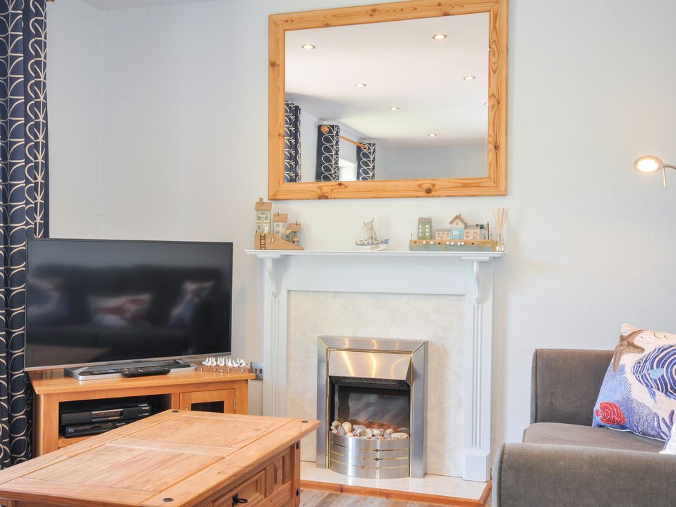 A living room with a television and coffee table at Columbine Cottage in Bude