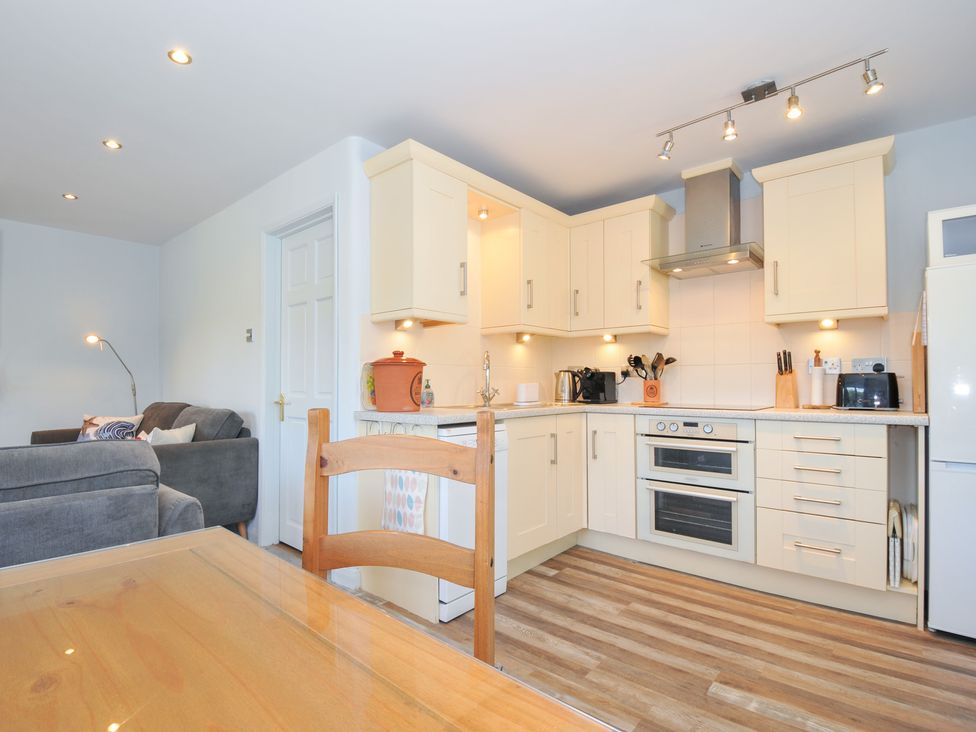 A kitchen with appliances and dining area at Columbine Cottage Bude