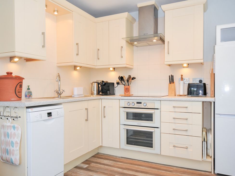 A kitchen with appliances and storage units at Columbine Cottage in Bude
