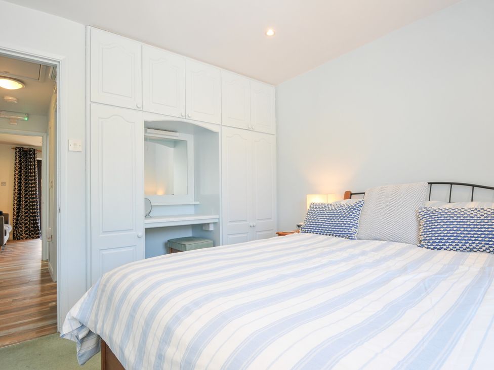 A bedroom with a bed and a dressing table at Columbine Cottage in Bude