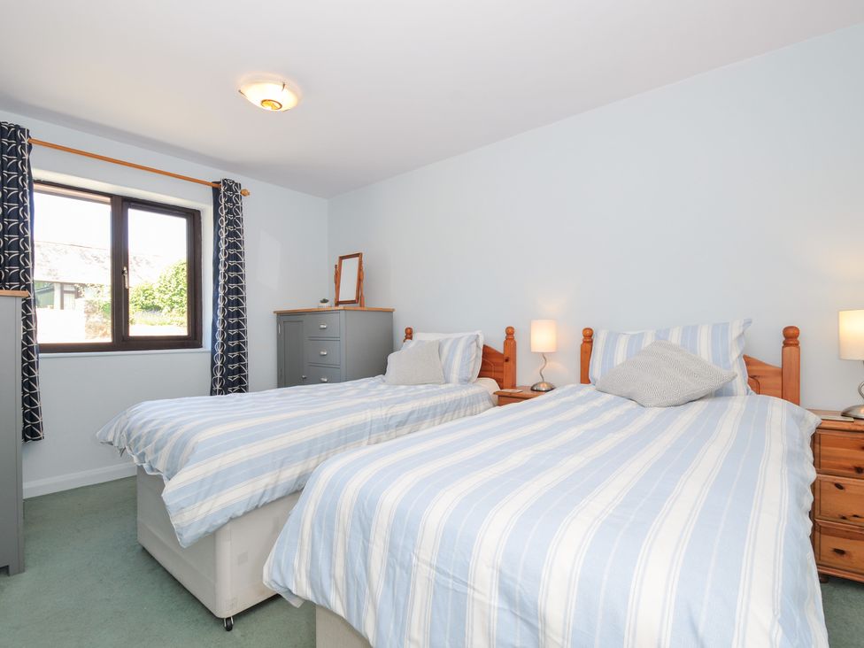 A bedroom with two beds and a mirror at Columbine Cottage in Bude