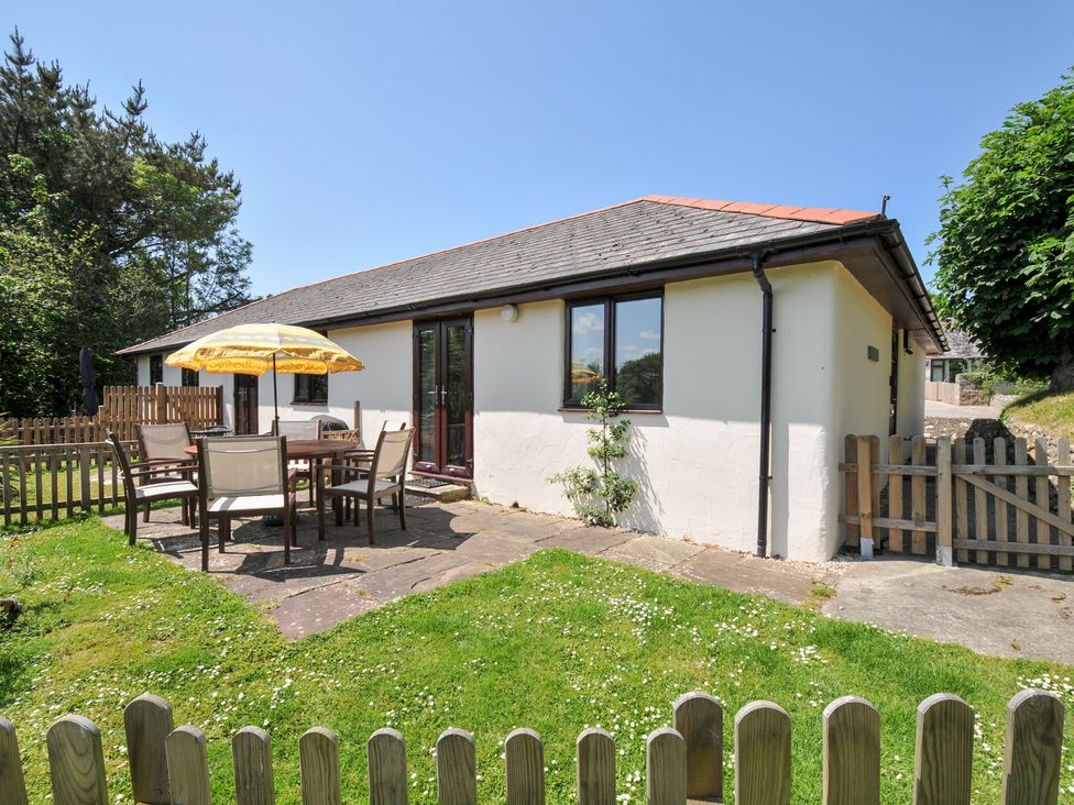 An outdoor dining area with a table and chairs at Columbine Cottage in Bude