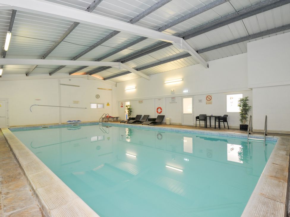 An indoor pool area with chairs and tables at Columbine Cottage Bude