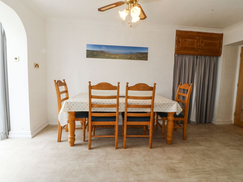 A dining room with a wooden table and chairs at Bryn Awel in Mynytho near Abersoch