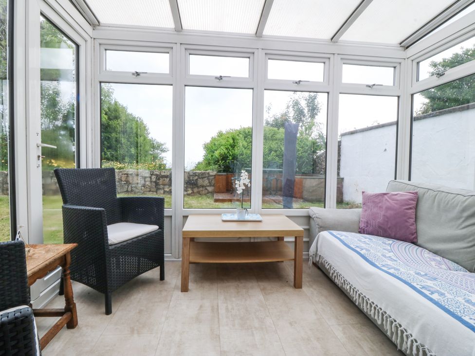 A conservatory with seating and a table at Bryn Awel in Mynytho near Abersoch