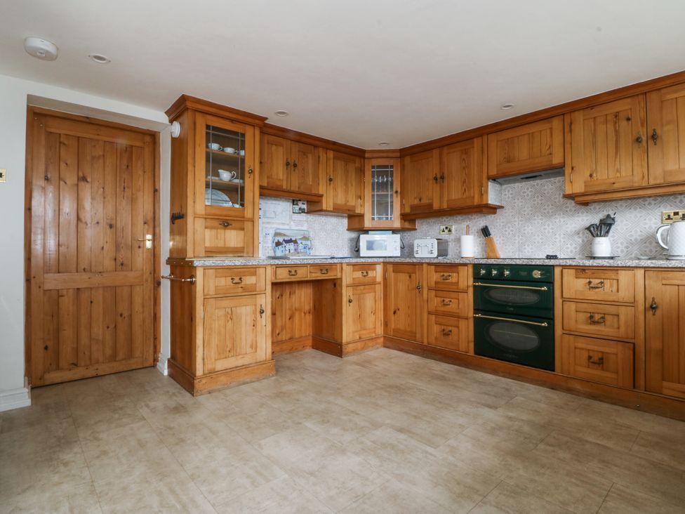 A kitchen with wooden cabinets and appliances at Bryn Awel Mynytho near Abersoch
