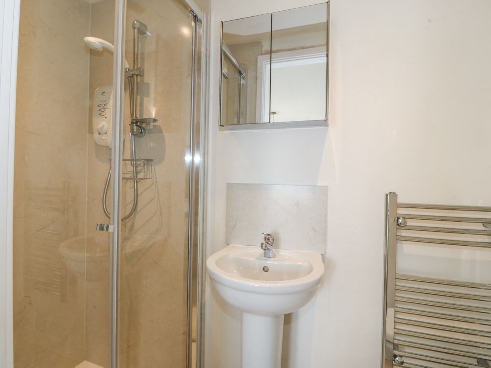 A bathroom with a shower, sink, and mirror at Bryn Awel, Mynytho near Abersoch