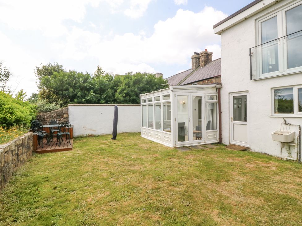 A garden with a conservatory and seating area at Bryn Awel Mynytho near Abersoch