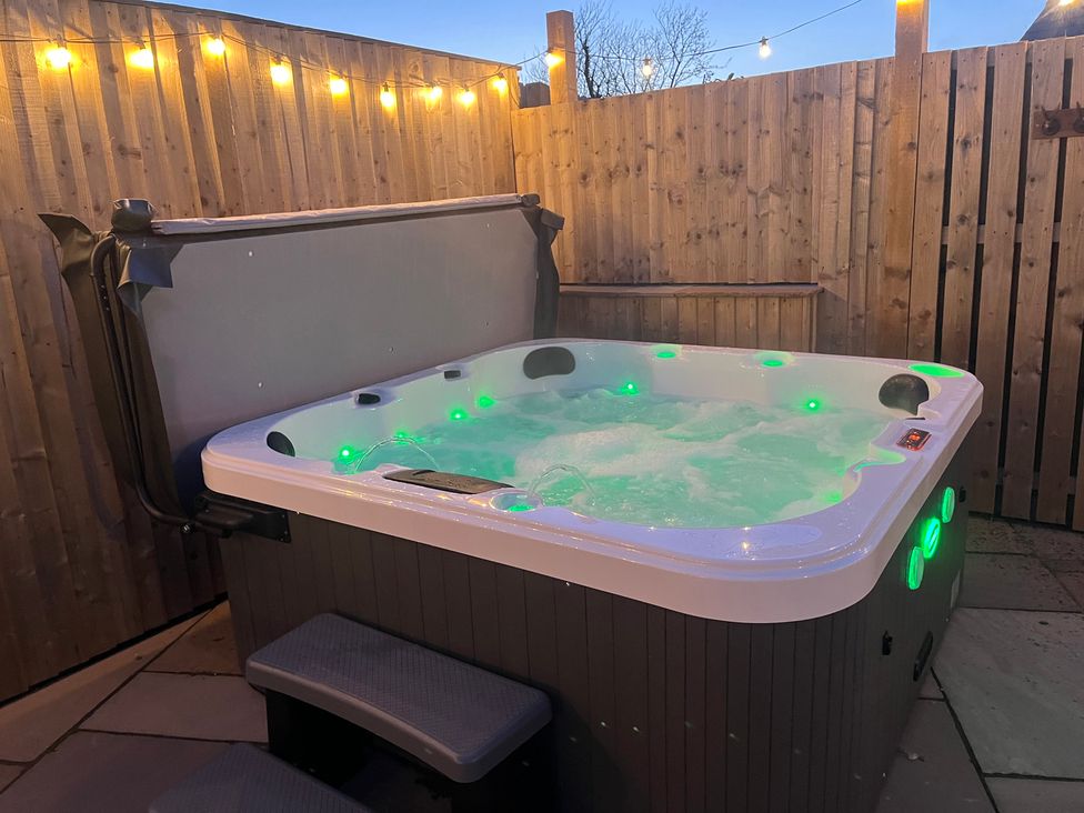 A hot tub with steps and wooden fence in an outdoor space at Gilfach in Abersoch