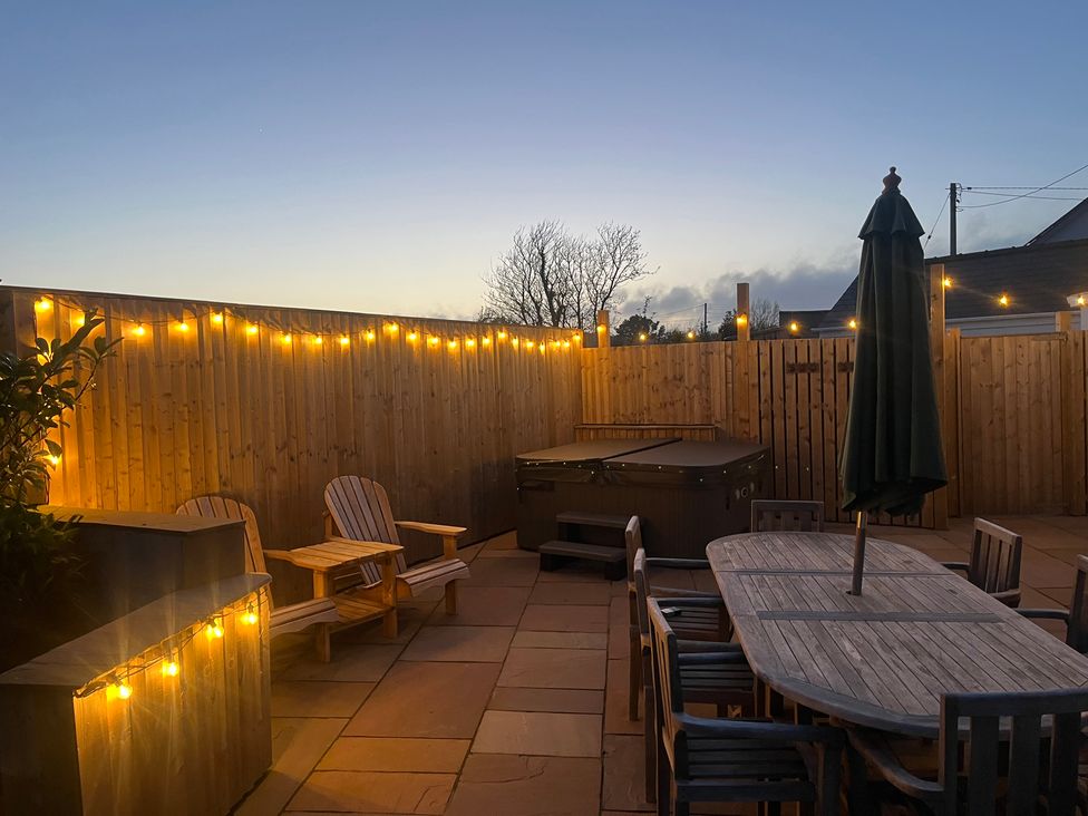 An outdoor area with a hot tub and dining table at Gilfach in Abersoch