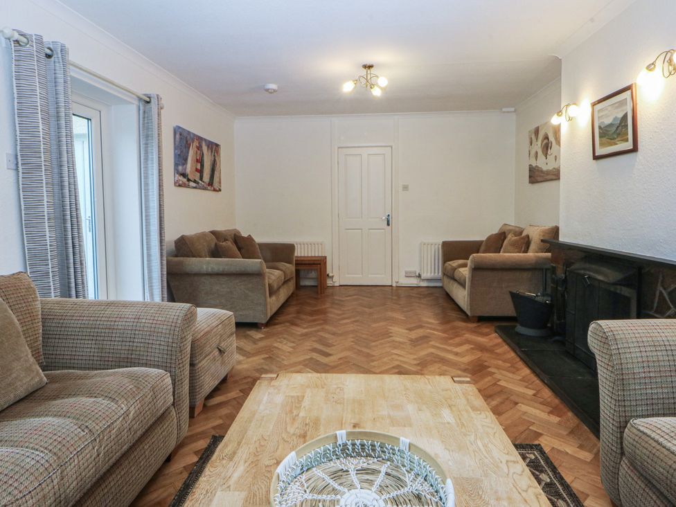 A living room with sofas, a table, and a fireplace at Lane End in Abersoch