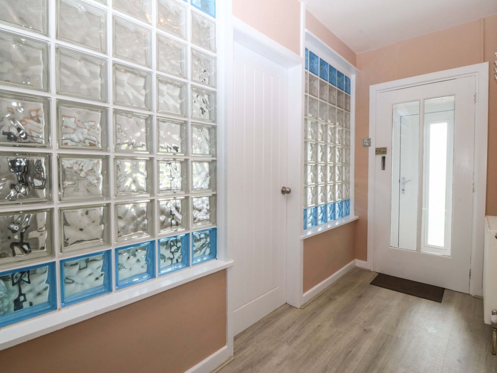 A hallway with glass brick wall and door at Nyth Y Fran Abersoch