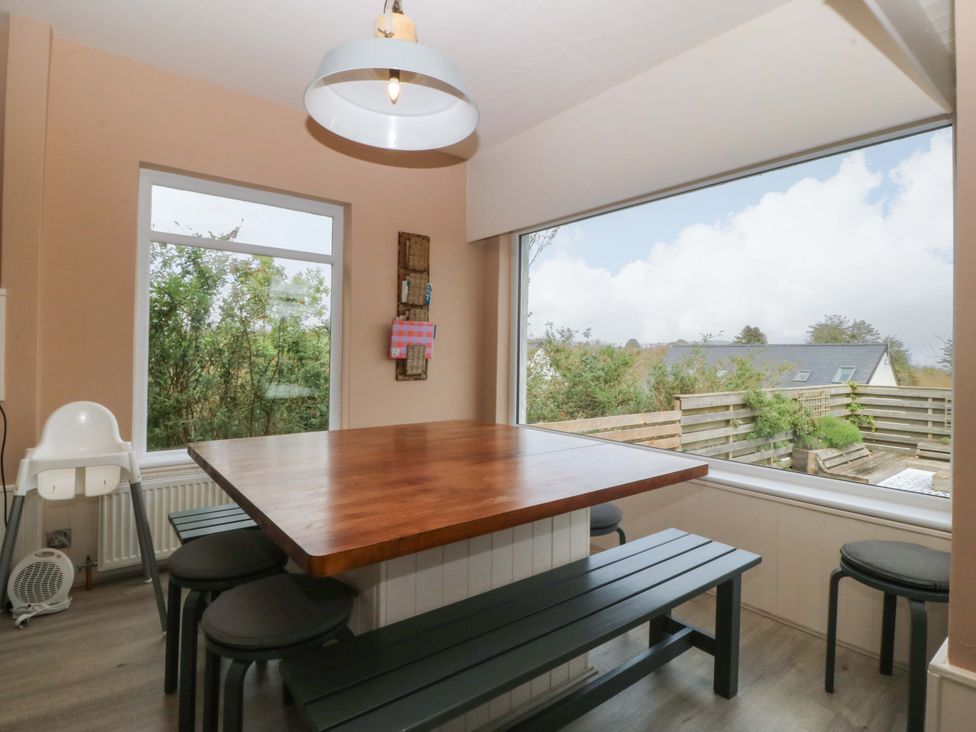 A dining room with a wooden table and chairs at Nyth Y Fran Abersoch