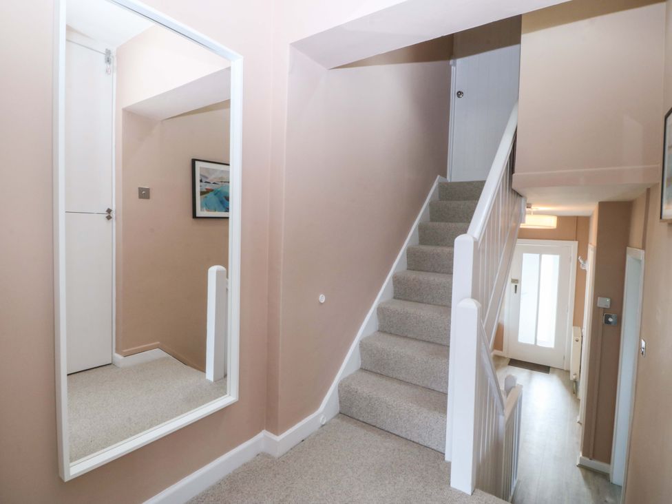 A hallway with stairs and a mirror at Nyth Y Fran in Abersoch