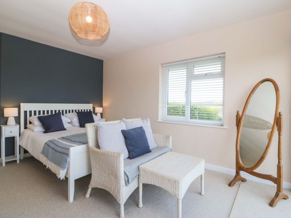 A bedroom with a bed and a mirror at Nyth Y Fran in Abersoch