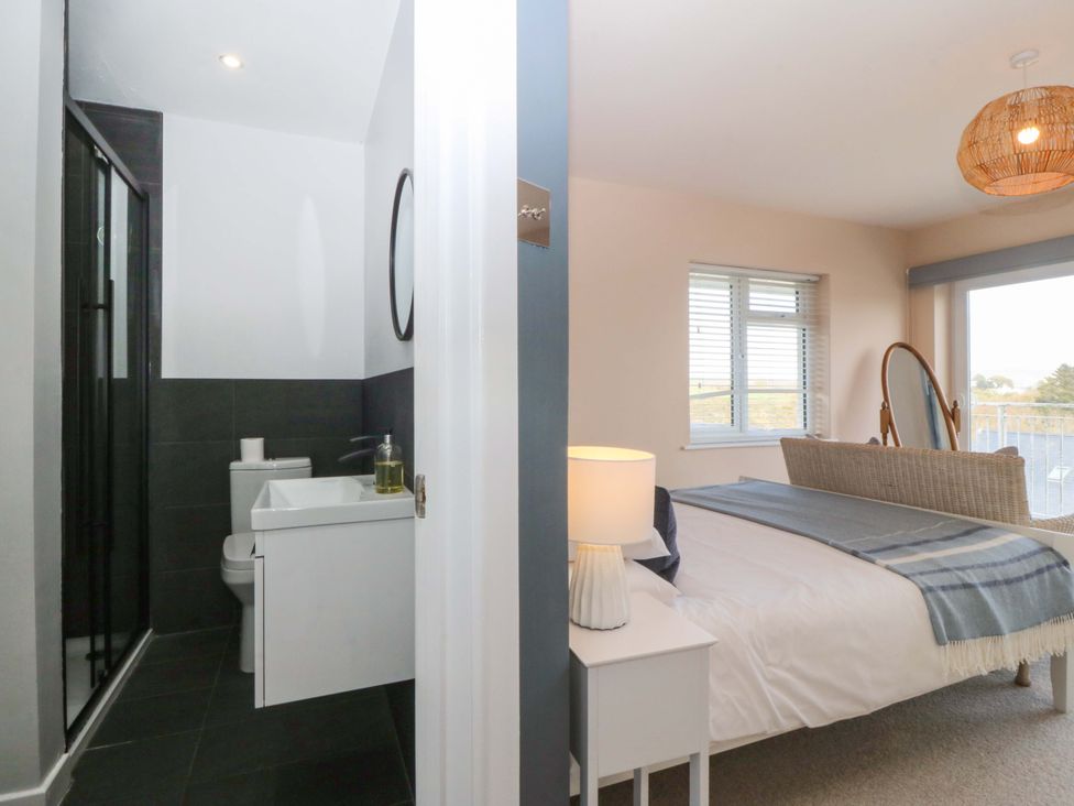 A bedroom with a bed and a bathroom visible at Nyth Y Fran in Abersoch