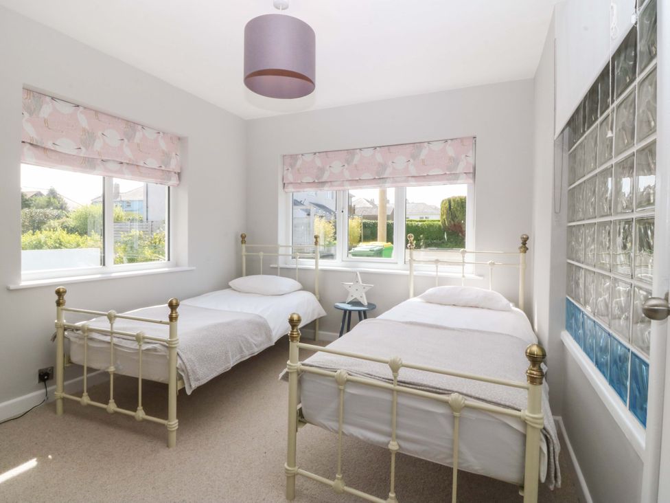 A bedroom with two beds and windows at Nyth Y Fran Abersoch