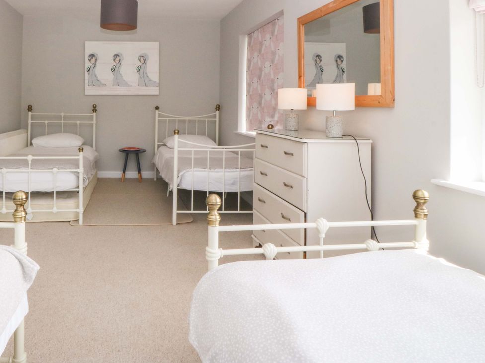 A bedroom with four beds and a dresser at Nyth Y Fran in Abersoch