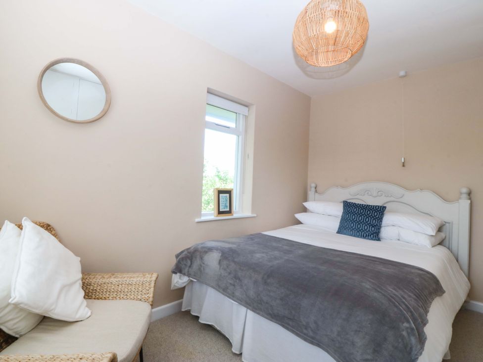 A bedroom with a bed and a chair at Nyth Y Fran in Abersoch