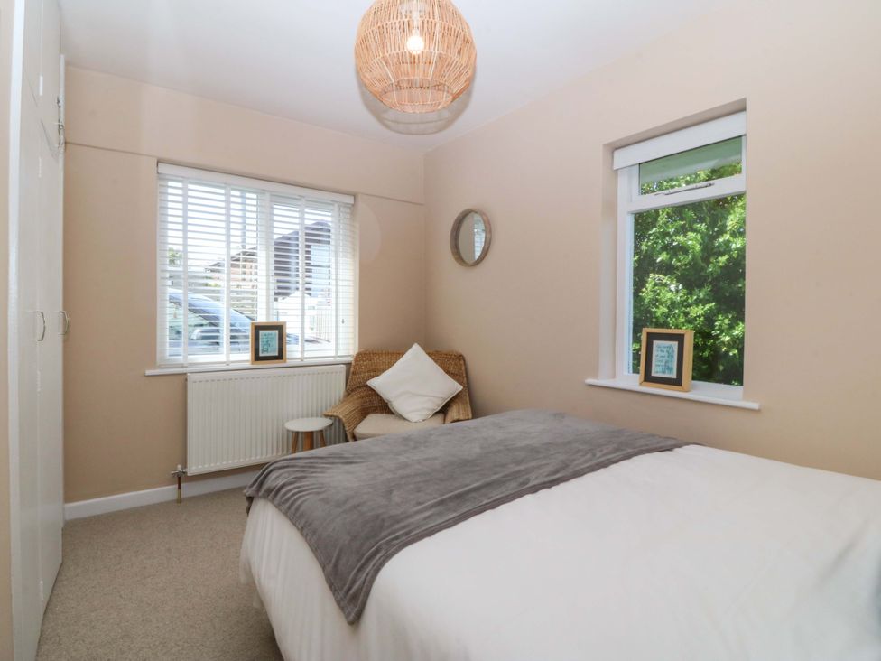 A bedroom with a bed and chair at Nyth Y Fran in Abersoch