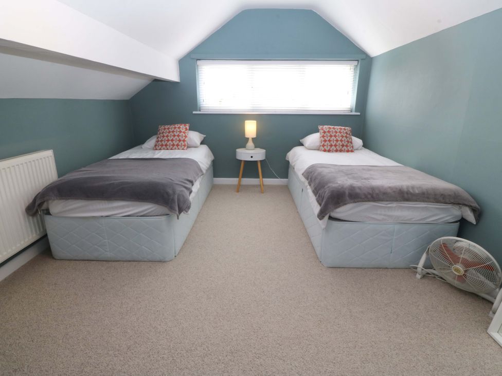 A bedroom with two beds and a lamp at Nyth Y Fran in Abersoch