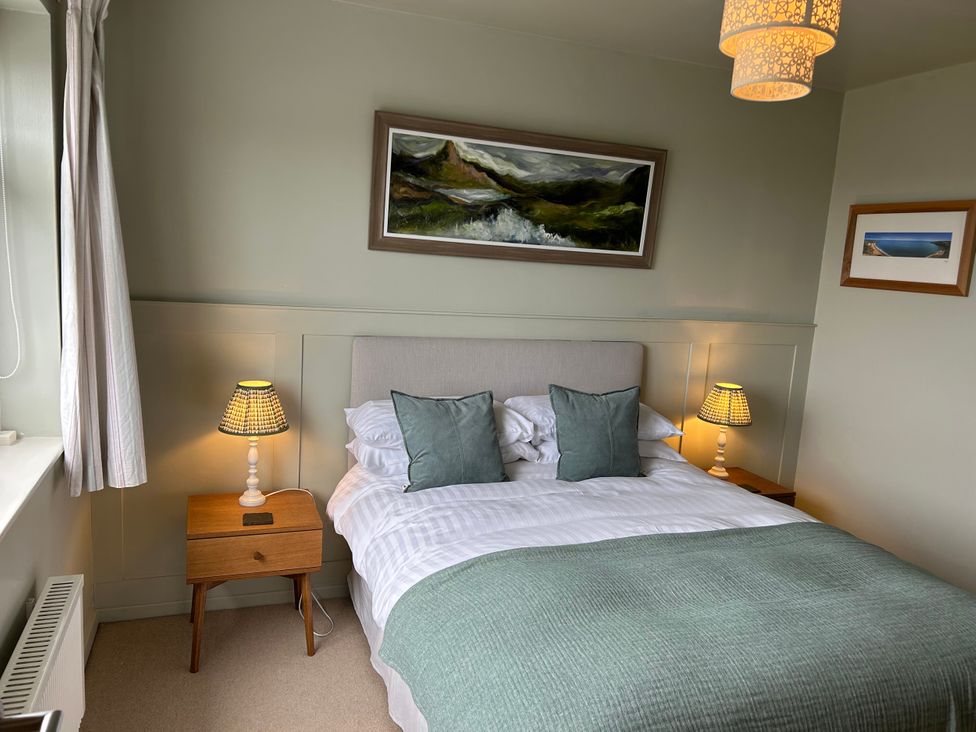 A bedroom with a bed and nightstands at The Anchorage in Abersoch