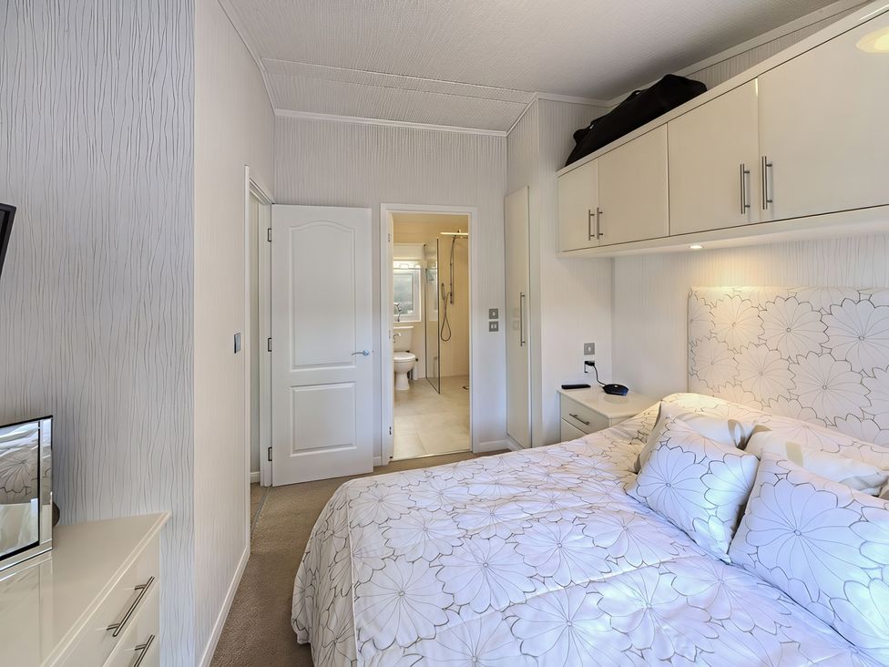 A bedroom with a bed and an ensuite bathroom at The Warren D7 in Abersoch