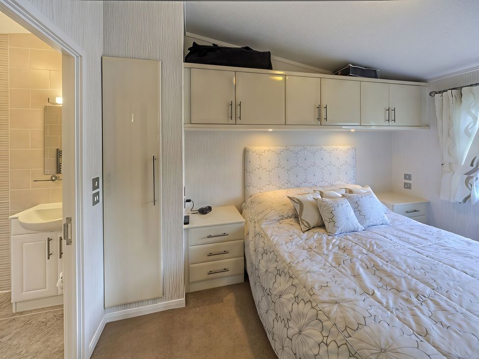 A bedroom with a bed and wardrobe at The Warren D7 in Abersoch