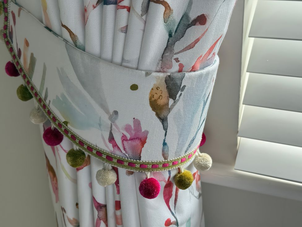 A colorful curtain with pom-pom trim at Ty Coed Abersoch
