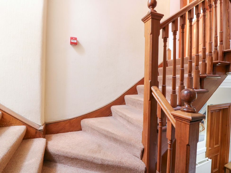 A staircase with carpet and wooden handrail at Tayview in Killin