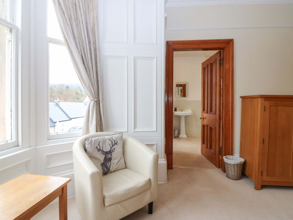 A living room with a chair and door leading to a bathroom at Tayview in Killin