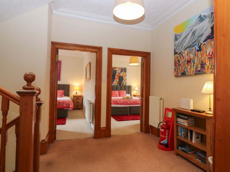 A hallway with access to bedrooms and a bookshelf at Tayview in Killin