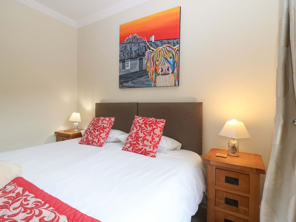 A bedroom with a bed, nightstand, and artwork at Tayview in Killin