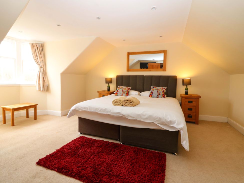 A bedroom with a bed, bedside tables, and a window at Tayview in Killin